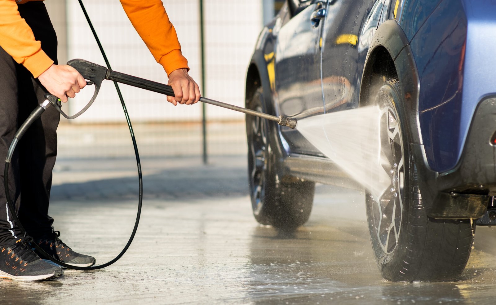 Closeup of male driver washing his car with contactless high pressure water jet in self service car wash. Paviour and Car Park Jet Washing